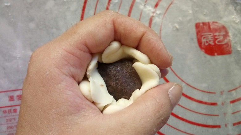 寿桃豆沙包,用虎口的手法包入馅,收口朝下放置。