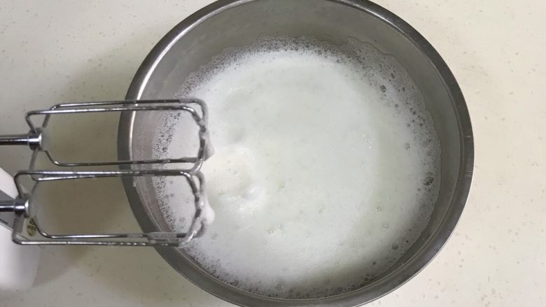 咖啡海绵蛋糕杯(分蛋法),打蛋器转中高速,蛋白打至细腻时,加入1/3细砂糖,继续搅打。