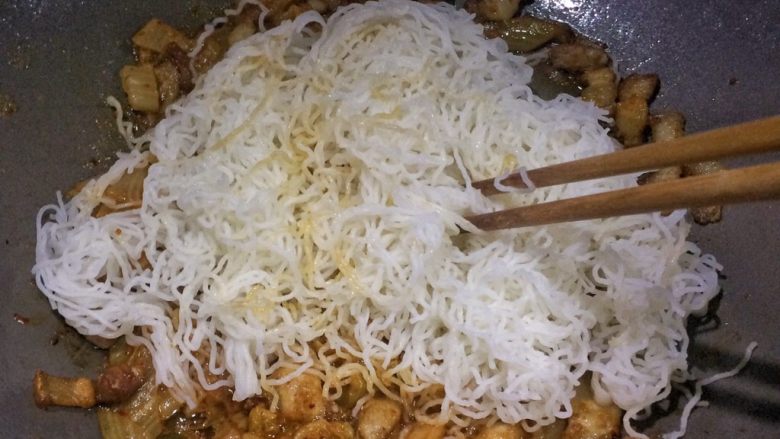 五花肉泡菜炒米粉,倒入米粉翻炒片刻,用筷子操作更方便。