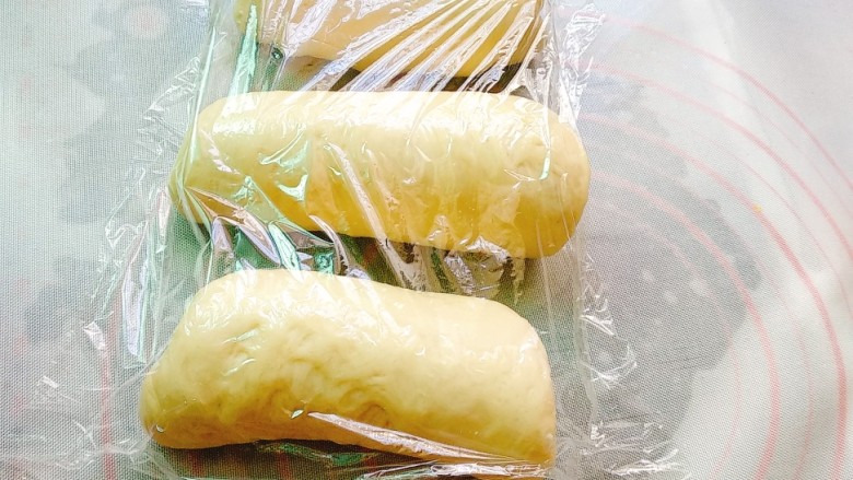 养乐多奶油吐司,擀成牛舌状,卷起来,盖保鲜膜继续松弛10分钟