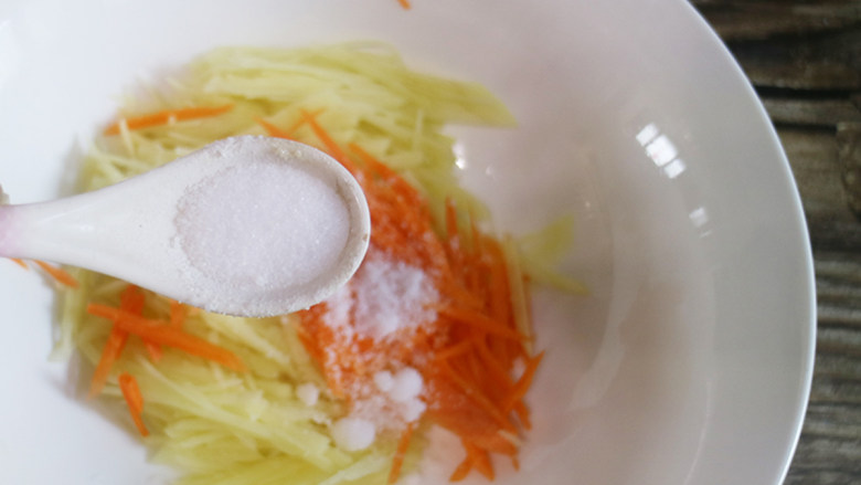 快手早餐 土豆丝饼,再将土豆丝和胡萝卜丝,加入盐进行调味,再进行搅拌。