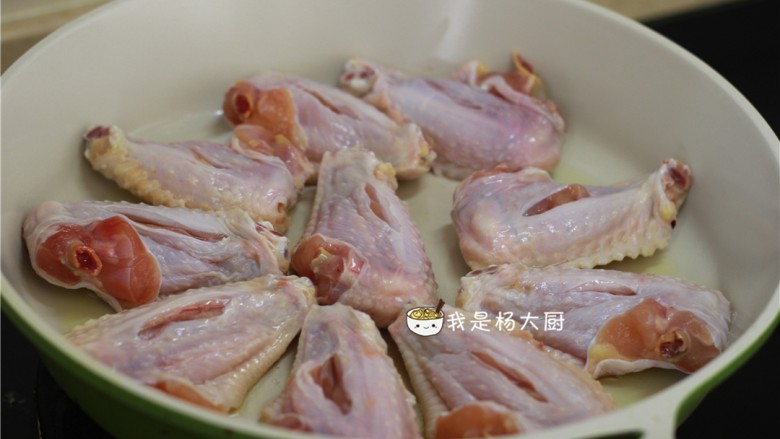 可乐鸡翅,不粘锅内放少许食油,将鸡翅的正面朝下(正面就是没有划一刀的那一面)