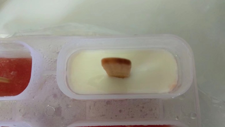 西瓜冰棒,倒入少量酸奶,不要倒满,预留出猕猴桃汁的空间。放入冰箱冷冻至彻底冻硬。