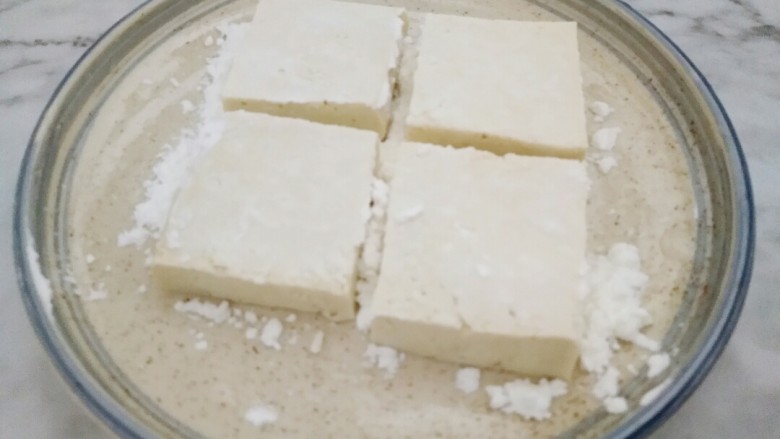 米饭杀手的家常菜~锅塌豆腐,淀粉倒入平盘中,把豆腐两面均匀粘上淀粉。