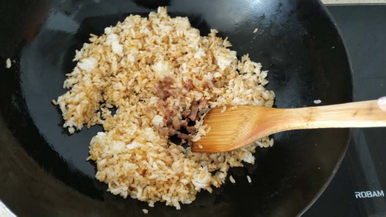 快手早餐 酱油蛋炒饭,第5步,米粒上色之后加入香肠丁,鸡蛋,继续翻炒均匀。