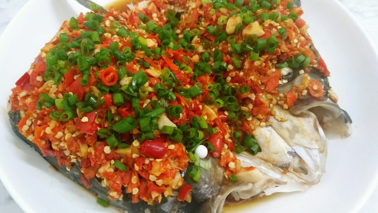 快手正餐 剁椒鱼头,鱼头蒸好后出锅倒掉上面的腥水和盘子里的葱姜蒜,淋上<a style='color:red;display:inline-block;' href='/shicai/ 864'>蒸鱼豉油</a>,撒上葱花。