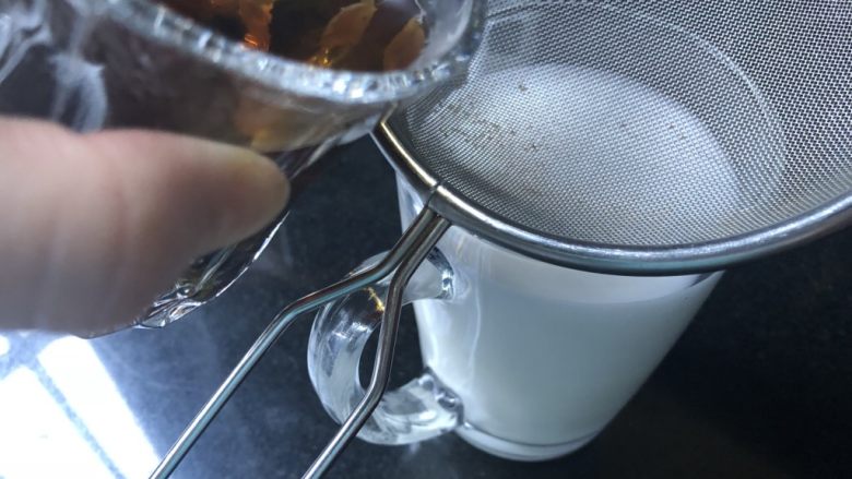 蜜桃乌龙奶茶,慢慢的将乌龙茶沿牛奶杯的边缘往下倒。注意茶汤现在还是比较热的,小心烫手。