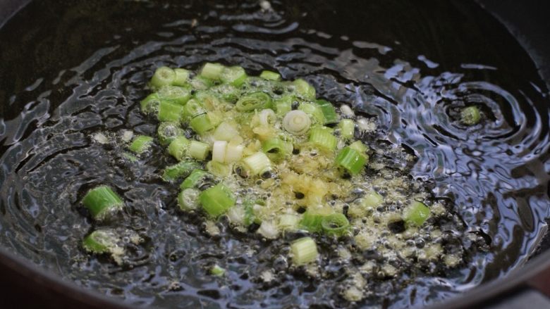 香菇肉酱拌面,锅中倒适量食用油烧热后,放入一半的葱花和姜末小火炒出香味