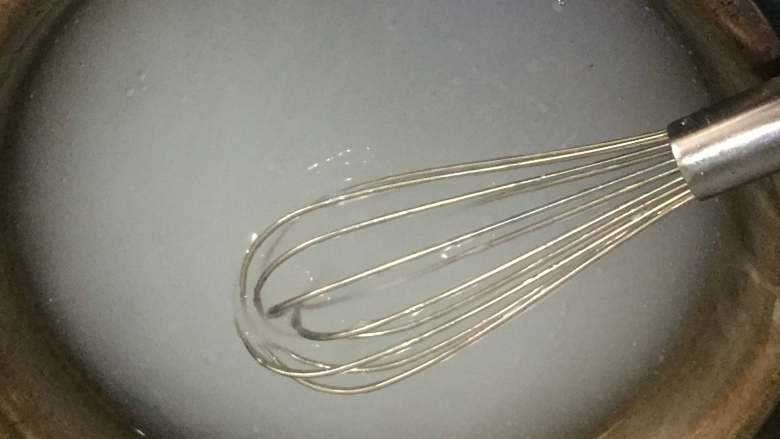 酸辣凉粉,紧接着,我们用蛋抽不停搅拌锅中的液体,此时转成小火,搅拌至锅中的液体变成透明即可。