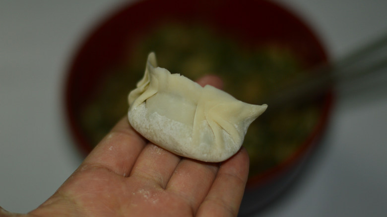 韭菜煎饺,将饺子皮对折,两边的皮捏紧,包成饺子状