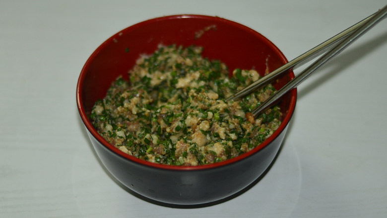 韭菜煎饺,将将蒜沫和韭菜都加入到猪肉碗中,搅拌均匀
