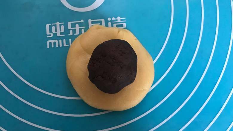 又香又脆~可可蛋黄酥,取一个分好的油皮,用手掌按压成圆饼,将一个油酥包裹起来。
