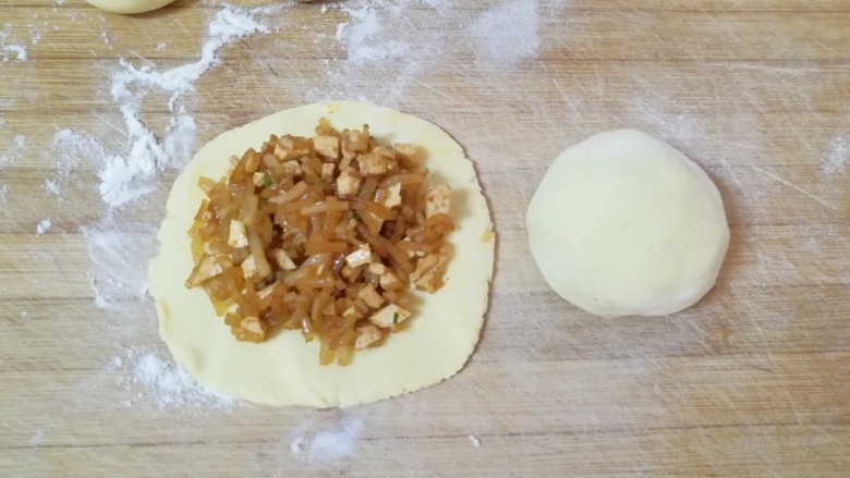 玉米面素菜包,取一个包子皮放入包子馅,像普通包包子一样包好,反过来整好形就可以了。