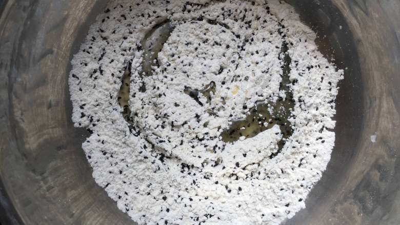 黑芝麻咸味普雷结,倒入玉米油和牛奶,用抓拌的方式混合均匀,面粉的吸水性不同可以适当调整牛奶的用量