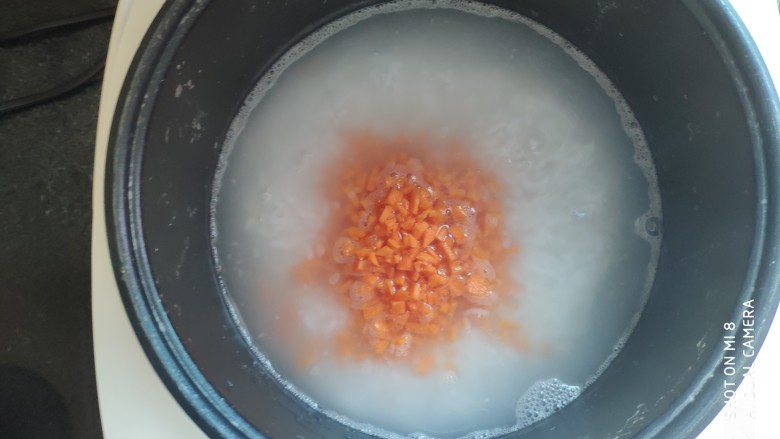 快手早餐 胡萝卜青菜瘦肉粥,粥煮好后先加胡萝卜,因为胡萝卜最难熟,继续煮10分钟
