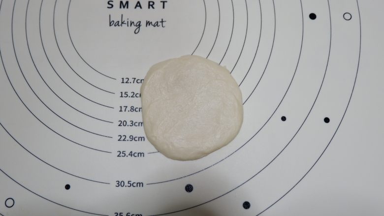 日式红豆包,醒发好取一个面团，翻过来底部向上，用手拍扁一些。
