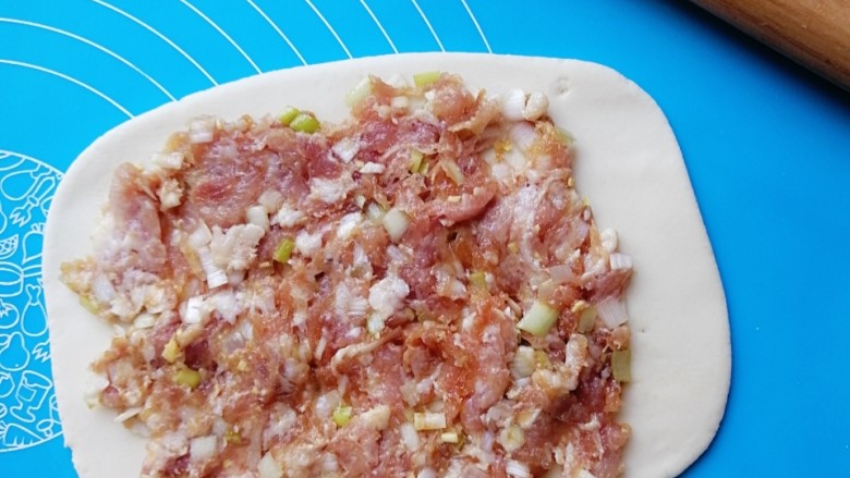 肉龙,揉好的面团,一分为二,取一份擀成长方形面片,铺上肉馅,尾部空出一段面皮