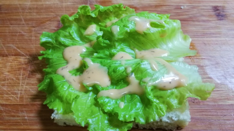 快手早餐 简便午餐肉三明治,准备一片面包,放上生菜,淋上法式沙拉酱
