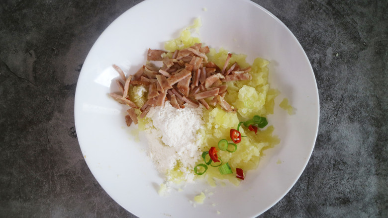 土豆培根饼,将蒸熟的土豆片用勺子碾压成土豆泥,再放入切好的培根和葱蒜末搅拌均匀,再倒入适量盐的<a style='color:red;display:inline-block;' href='/shicai/ 519'>面粉</a>,直至融合。