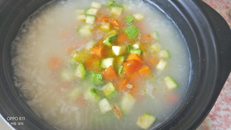 快手早餐 双色营养砂锅粥,把翻炒好的西葫芦,胡萝卜舀入砂锅里再中火蒸五六分钟至熟透