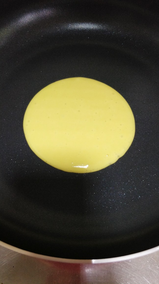 快手早餐 原味鸡蛋松饼,一定要用平底不粘煎盘哦,开小火,要四周和中心都有火的那种小火,这样子上色才均匀,等锅热后从煎盘中间正上方10厘米处缓慢倒入一勺面糊