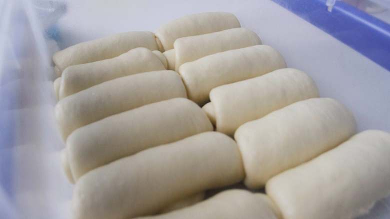 胖墩牛奶面包,松驰好的面团取出，分成每个约60g，卷成圆柱状，盖好醒发15分钟。