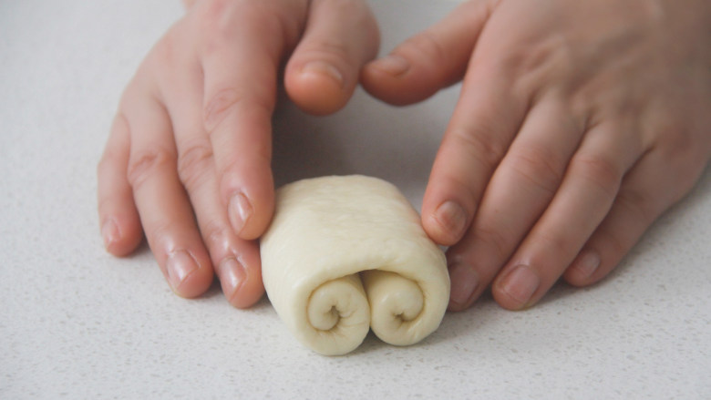 胖墩牛奶面包,将面片从上下两端分别卷至面皮中间位置，贴合好后翻面排入烤盘。