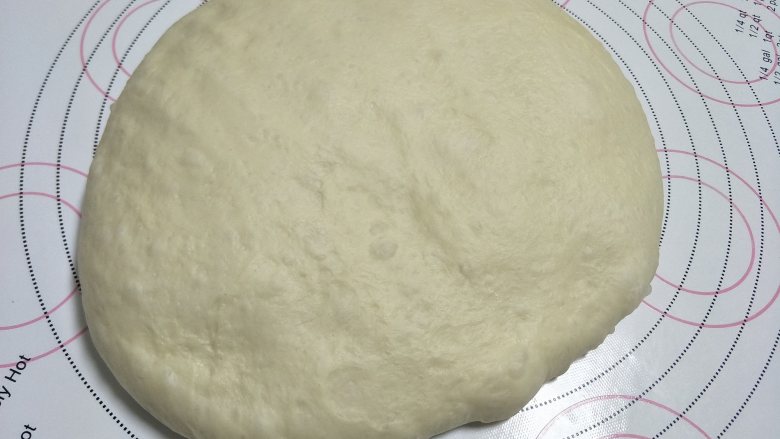 烘焙入门级基础小餐包,检查好状态后,需要对面团进行排气。取出面团放到揉面垫上,用手取轻轻的压着排气,不要太使劲,不用压的一点气泡都没有,因为下一步,我们还要再排气的。