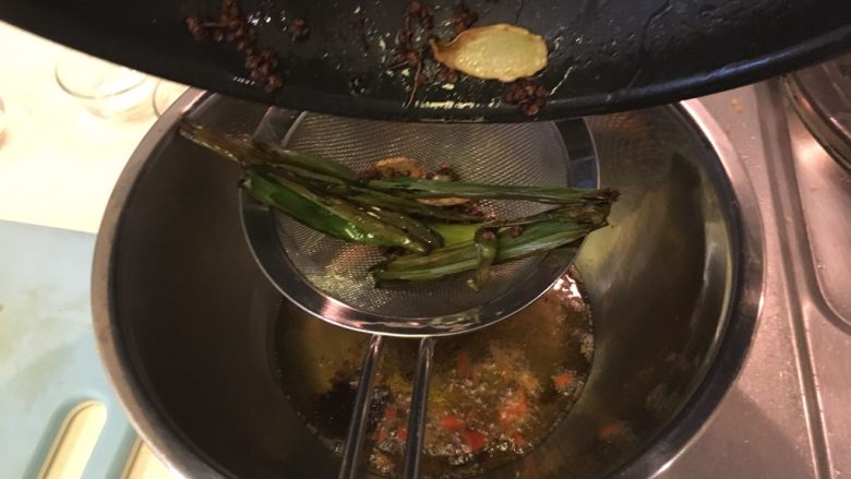 怪味口水鸡,用滤网将炒香的菜油加入大碗里,浸泡1分钟