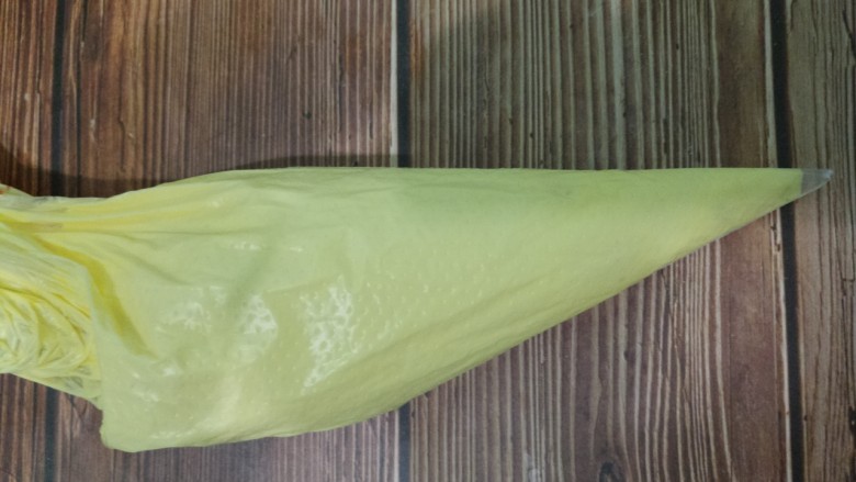 蛋黄溶豆,把蛋黄糊倒入裱花袋中,前面剪一个小口。