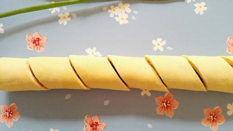 豆腐卷,豆皮包裹着蛋皮和蔬菜从下往上卷起来,用刀将豆皮卷切成段即可装盘食用。