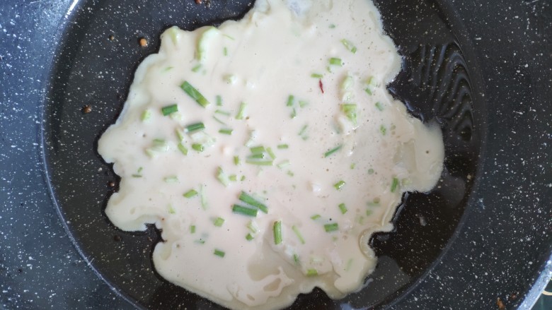 快手早餐之葱花饼,锅里刷上一层油,用大勺子舀面糊入锅,旋转一下锅,让面糊均匀,一面煎好在翻面煎另一面
