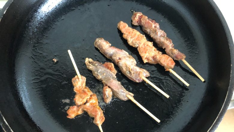 孜然猪肉串,将白芝麻撒在烤好的肉串上面,即可摆盘。