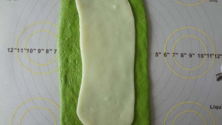 菠菜麻薯夹心软欧包,松弛好的面团擀开用手稍微整理成长方形,麻薯也擀成长方形放在面团上面