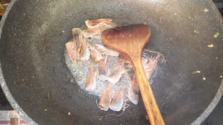鲜虾蘑菇炒面,锅内倒入多一些的油,把虾头放入炒出虾膏,用锅铲按压虾头挤出虾膏