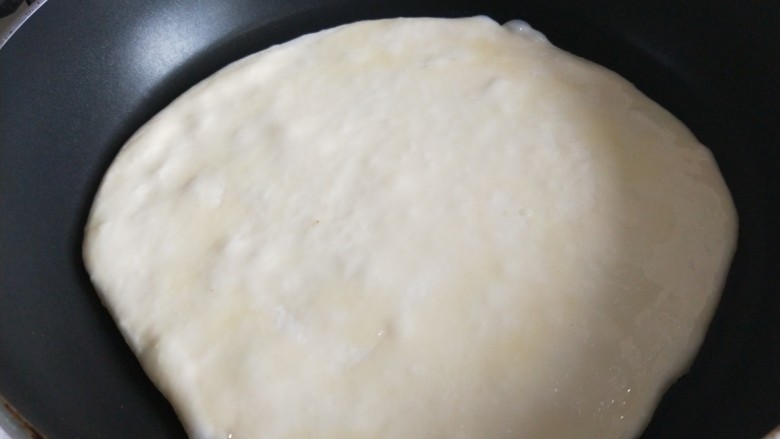 新文美食 千层饼,把擀好的饼放锅中,面上刷一层油。
