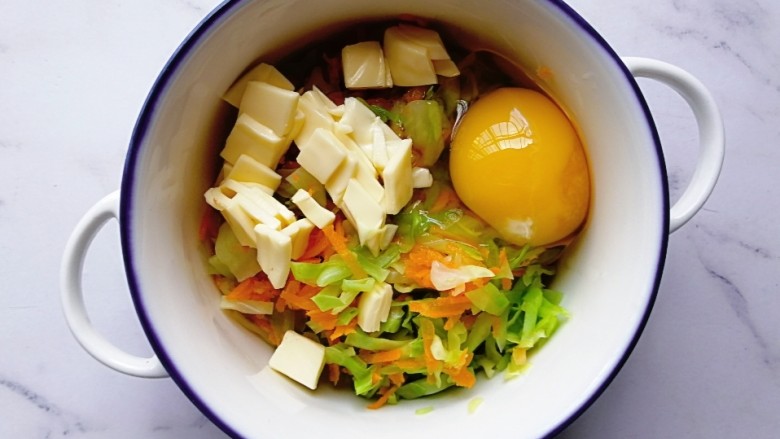 卷心菜胡萝卜奶酪蛋饼,焯好的胡萝卜、卷心菜和<a style='color:red;display:inline-block;' href='/shicai/ 9'>鸡蛋</a>、奶酪片放入一个碗内,搅拌均匀