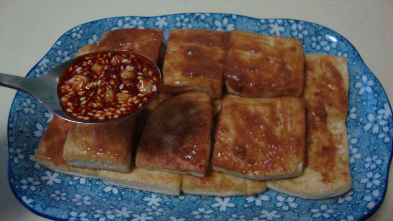 香煎豆腐,豆腐上刷层芝麻酱,把炒好的麻辣料汁浇上面