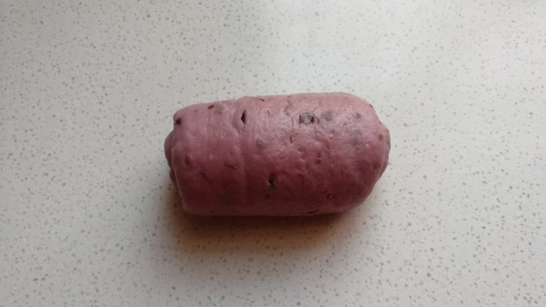 淡奶油紫薯蜜豆吐司,把擀好的长舌状面片再次从底部向上卷起来,卷好后摆放入吐司盒中。