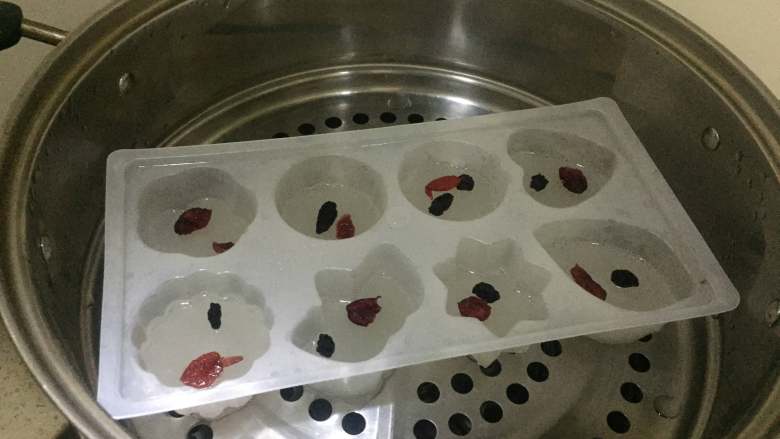 双色水晶糕,三分钟过后,打开锅盖, 可以清楚的看到面糊由之前的乳白色变成了透明的,此时表面已经凝固,可以放一些自己喜欢吃的果干。