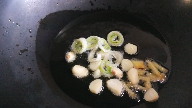 新文美食 油焖豇豆,锅中放入适量油烧热,放入葱姜蒜炒香。