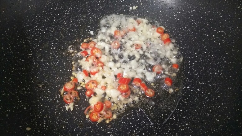 夏天开胃小菜~凉拌金针菇,锅内倒入适量油,倒入小米椒和蒜末炒香。