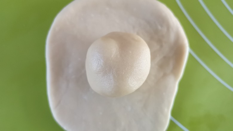 蛋黄酥,取一份水油皮擀成圆饼后放上一份油酥包起来，口收紧并朝下