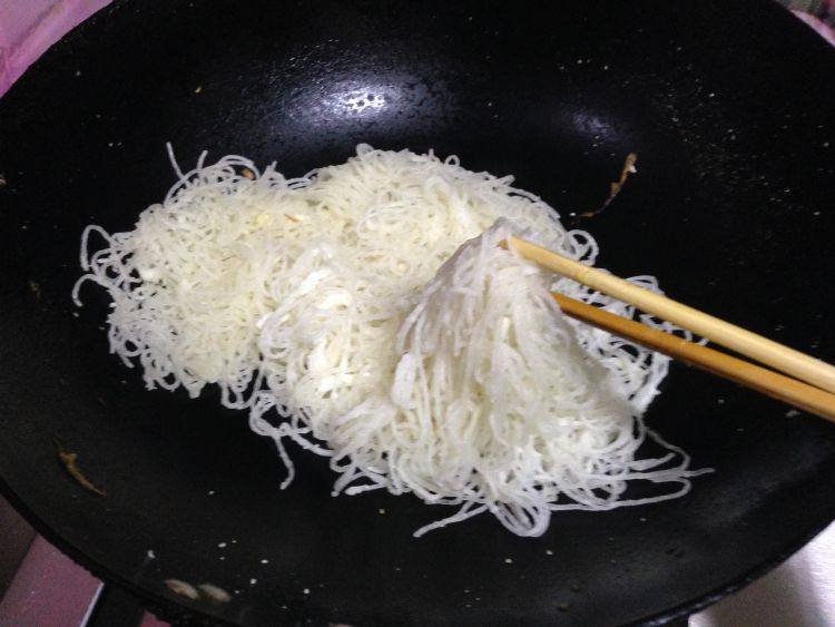 韭菜鸡蛋炒粉丝,炒锅另加油,放入裹上面粉的粉条翻炒,为防止粉条粘连,用锅铲和筷子一 起,边翻边抖散,盛出备用