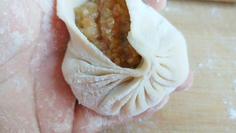 新文美食 猪肉白菜包子,拇指捏住往前推缩捏出褶皱。