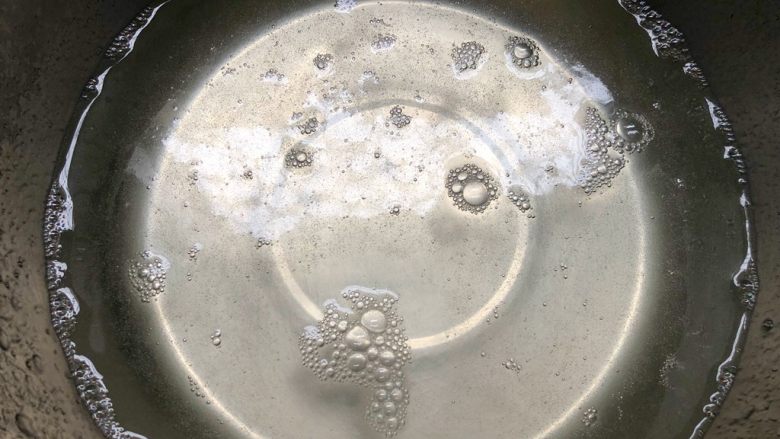 自制水果果冻,把碗放到电磁炉上,开火把水烧开,用勺子把白糖搅拌至溶化