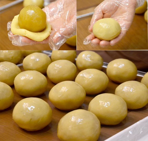 广式蛋黄莲蓉月饼,取一份饼皮压扁后包入莲蓉蛋黄馅料,用虎口把饼皮慢慢向上推,最后揉搓至饼皮完全包裹住馅料,收紧口,间隔开放在烤盘。