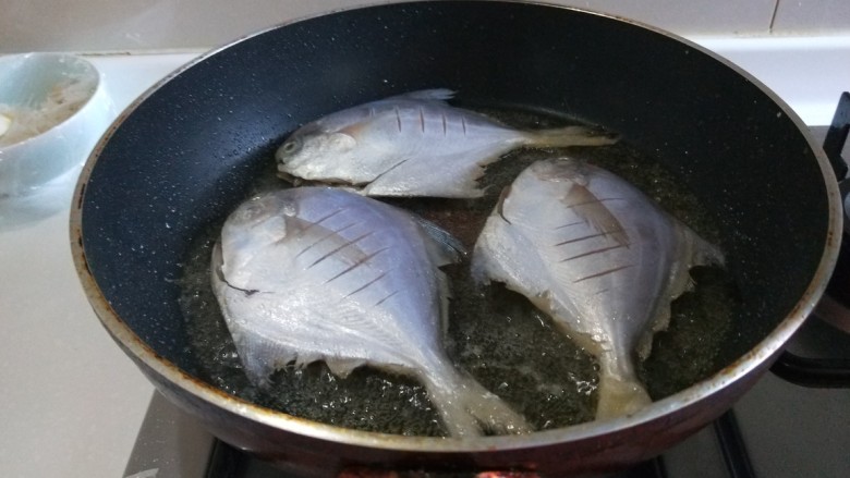 新文美食 香煎小平鱼,平台锅烧热倒入适量油,放入三条平鱼煎制。