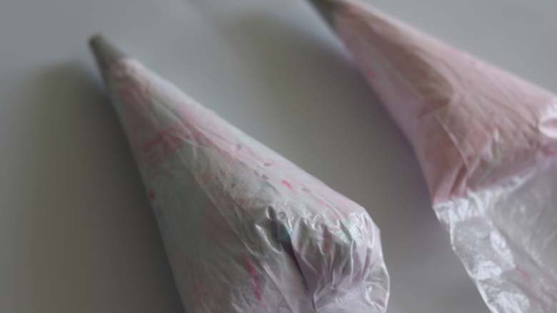 甜蜜蛋白糖 治愈系小确幸,裱花袋装好裱花嘴,放置到高的杯子中。俩部分蛋白霜,分别放到裱花袋中,排出空气,扎紧上口。