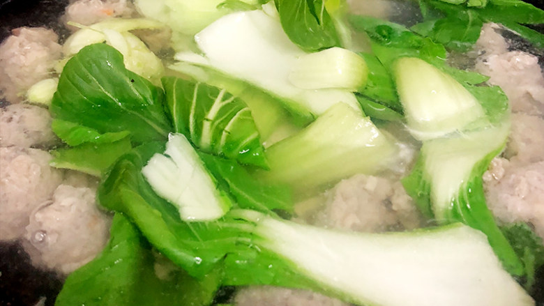营养美味的丸子豆腐汤,将豆腐片和油菜放入锅中,大火煮开。